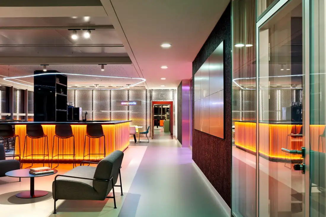 Corridor along glass meeting rooms leading to the lit bar counter