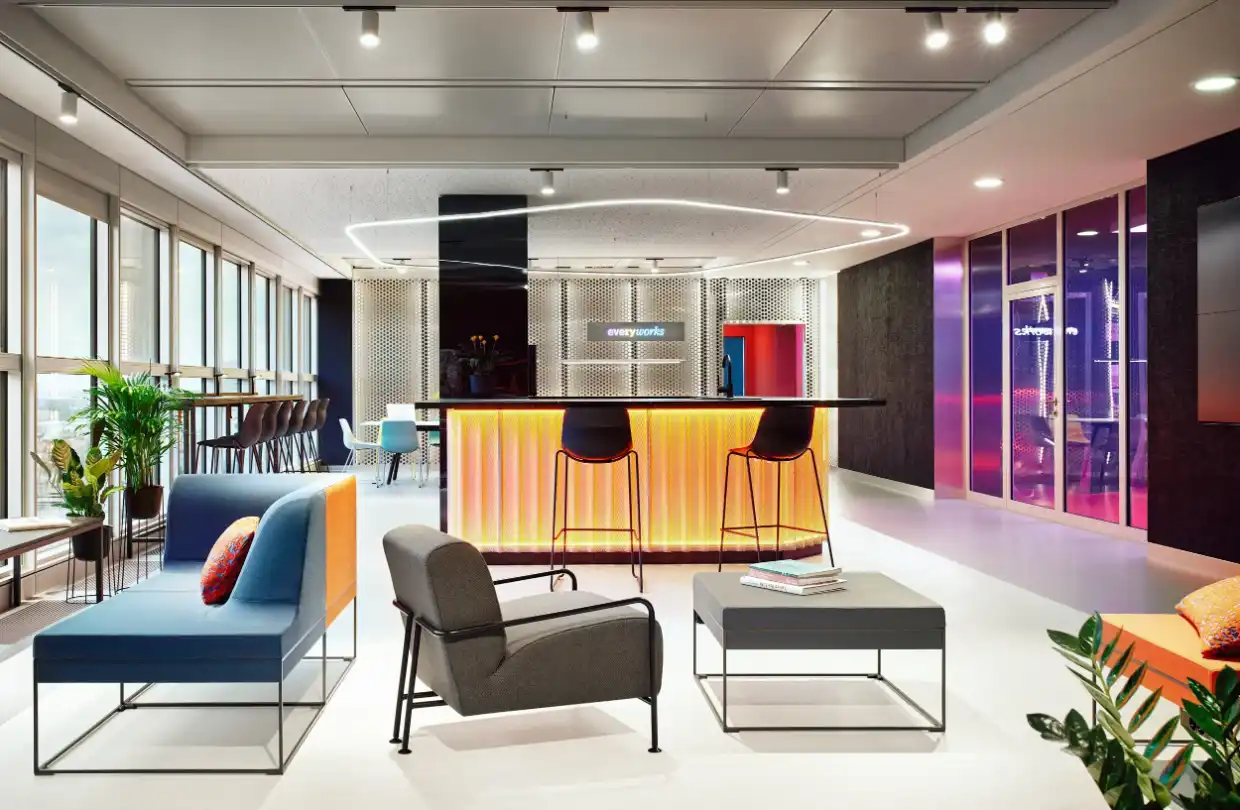 everyworks lounge at Berlin Hauptbahnhof with a glowing bar counter, sofas and city view