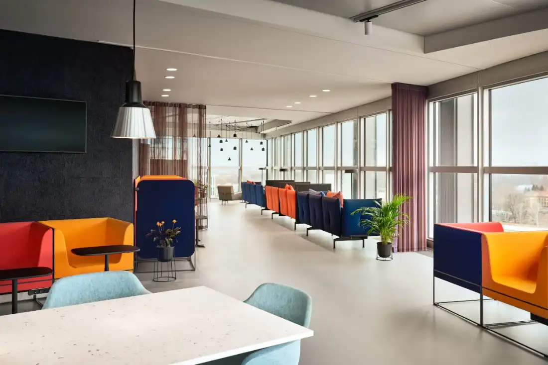 Open workspace with orange and blue booth seating along a window front